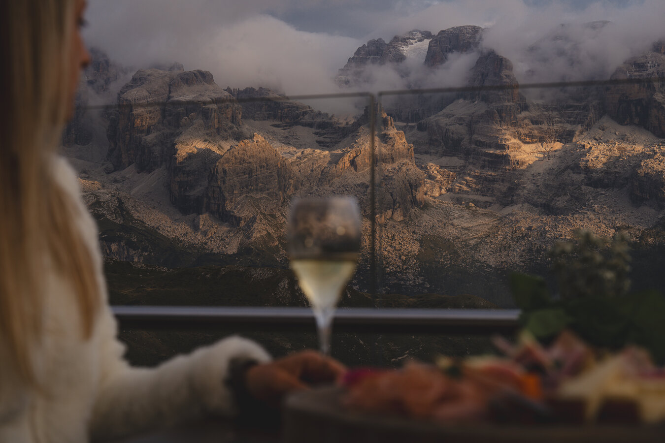 Donna con bicchiere di vino davanti a montagne rocciose nebbiose