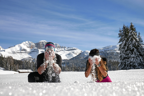 Zwei Personen im Schnee, Gesichter verdeckt, genießen eine spielerische Szene.